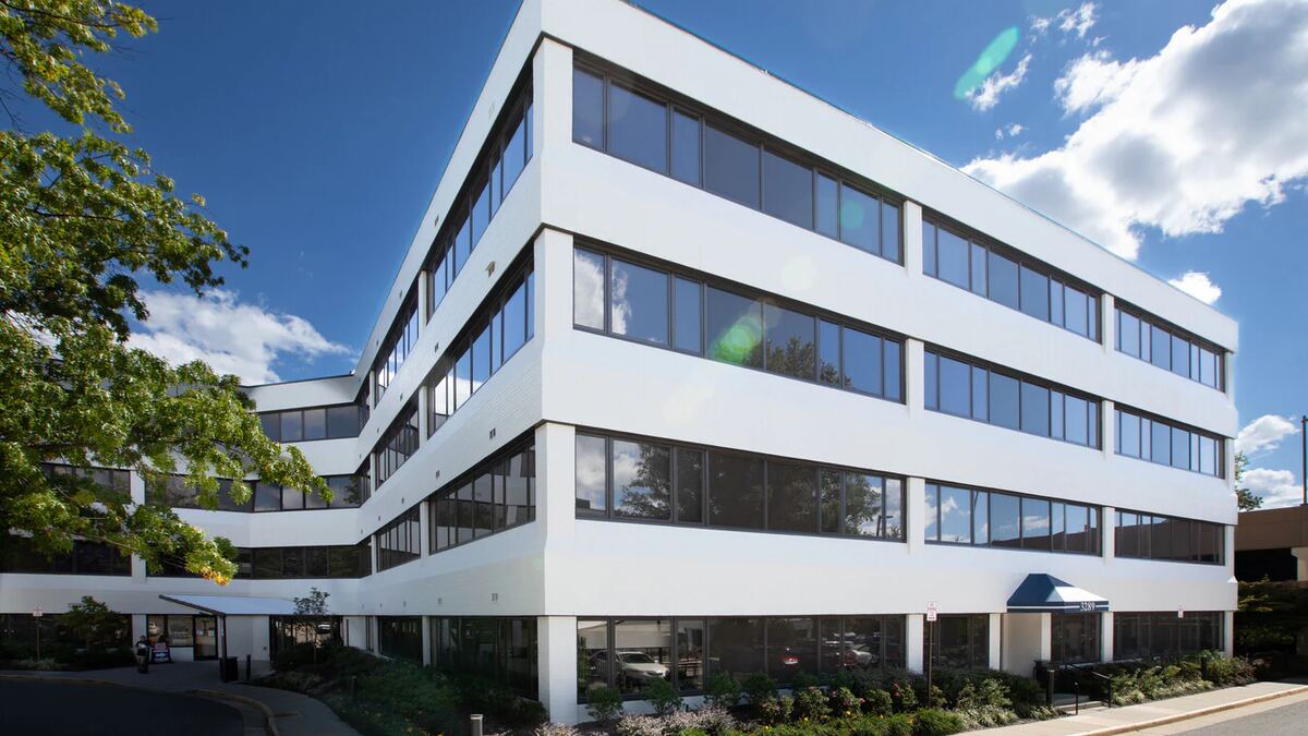 The four storey white office building at 3299 Woodburn Road, seen from the corner on a clear day.